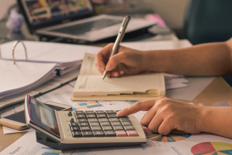 A calculator resting beside a calendar on a desk, illustrating an on-time monthly payday deadline for employers under the UAE Wage Protection System rule.
