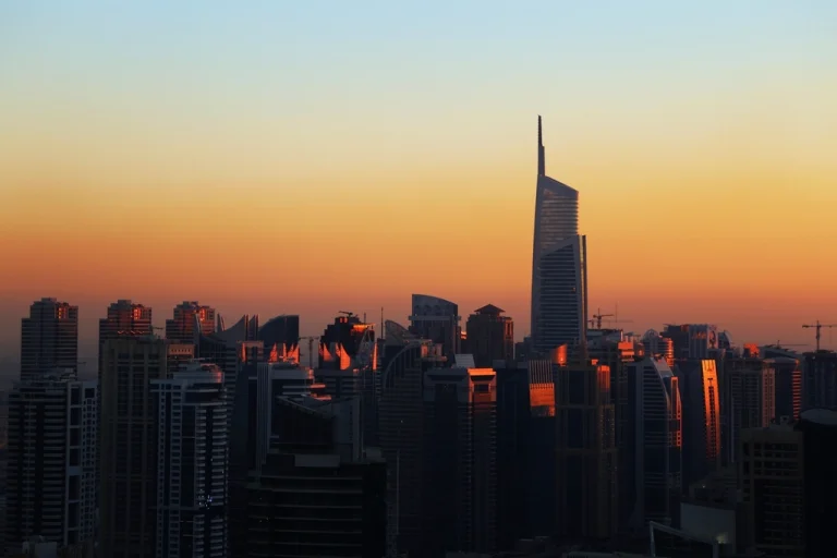 Dubai skyline silhouetted against a glowing orange sunset, representing the UAE's sponsor-free residency routes - the 5-year Green Visa, the 12-category Golden Visa, and the 10-year Blue Residency.