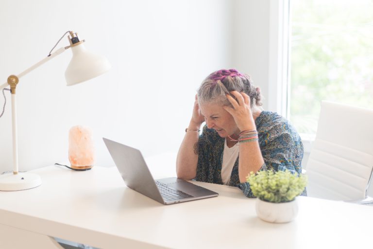Woman working at an office desk with a laptop and paperwork, reviewing records in a corporate setting reminiscent of a Golden Visa compliance and duty-of-care check.