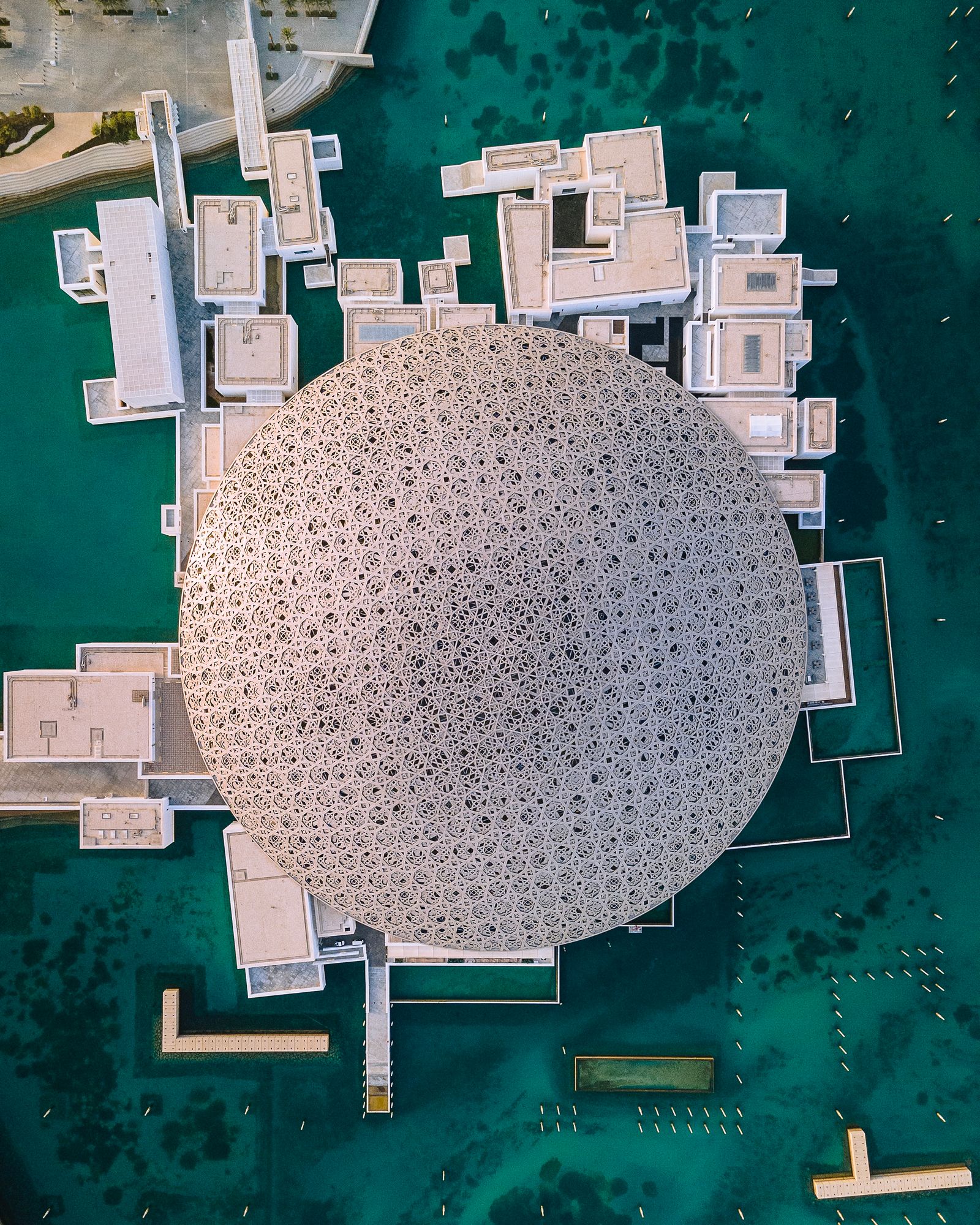 Aerial view of the Louvre Abu Dhabi's domed roof and surrounding waters on Saadiyat Island, illustrating Abu Dhabi's investment-zone island coastline for families