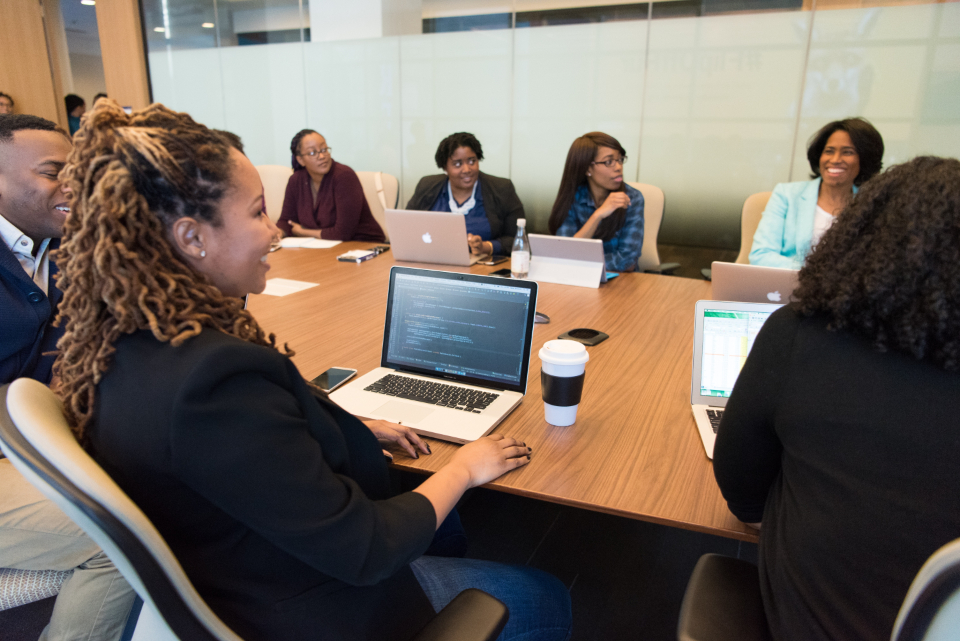 Professionals around a long conference table in a modern glass-walled corporate boardroom, illustrating a Regional HQ office and executive team meeting in Riyadh